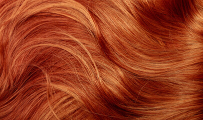 Red hair close-up as a background. Women's long orange hair. Beautifully styled wavy shiny curls....