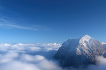 Fototapeta premium Mountain peak above clouds and blue sky, aerial view
