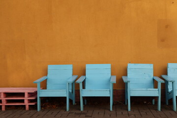 Wooden chairs arranged in a line against a wall