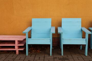 Two empty wooden chairs arranged in a line against a wall
