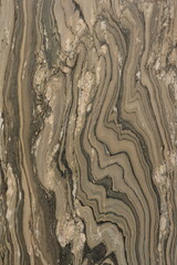 surface marble close-up wavy patterns with various shades of beige, brown, and dark gray.
