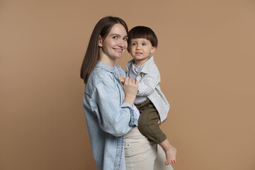 Family portrait of happy mother with her little son on beige background
