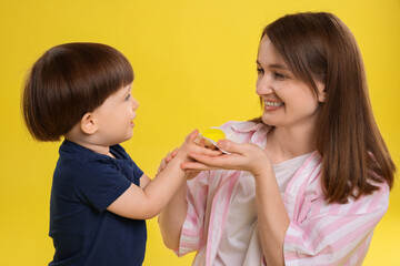 Mother and baby eating tasty mochi on yellow background