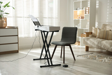 Synthesizer with music sheets and chair indoors