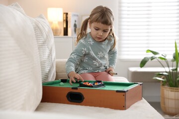 Cute little girl playing billiards at home