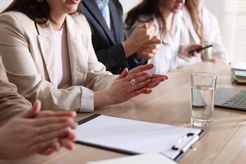 People applauding at table in office, closeup