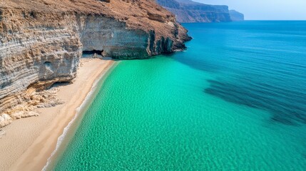 Aerial view capturing crystal clear turquoise waters lapping against a pristine sandy beach nestled between rugged cliffs in musandam peninsula, oman