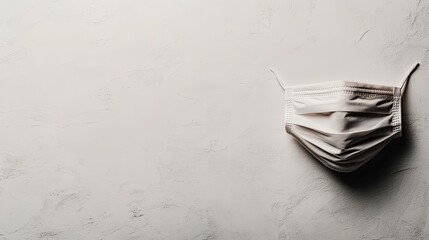 White medical face mask on light textured surface highlighting health and safety theme