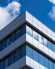 Modern Architectural Design Featuring Reflected Clouds in Glass Windows Against a Blue Sky