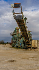 Huge old machine for sand extraction in a lagoon with a mobile conveyor belt