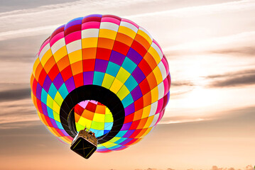 Colorful hot air balloon flying under orange sunset sky	