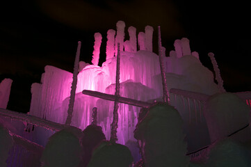 ice tower illuminated with pink LEDs and decorated with icicles at night
