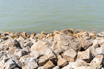 Rocky shoreline with calm water in sunlight. Lake Balaton, Hungary