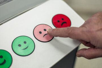 Customer pressing a slightly dissatisfied button on a feedback machine closeup
