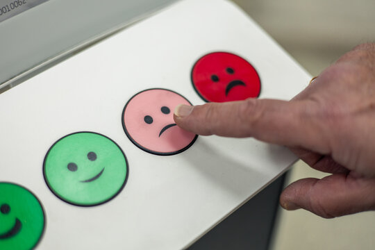 Customer pressing a slightly dissatisfied button on a feedback machine closeup