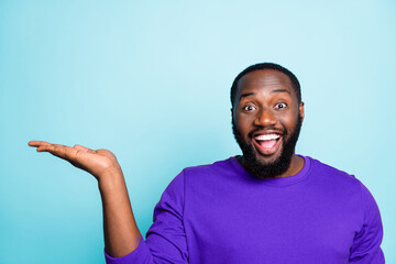 Close up photo of funny dark skin guy holding open palm empty space advising new product with low...