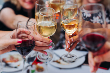 Group of guests celebrate and raise glasses, toasting and cheering with alcohol glasses with wine...