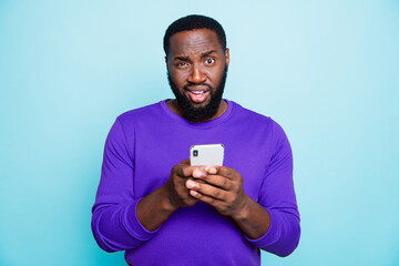 Photo of unsure man mixed-race looking at you with arrogance holding telephone browsing through...