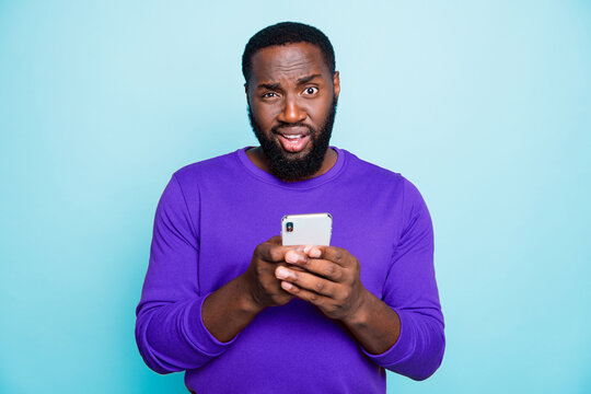 Photo of unsure man mixed-race looking at you with arrogance holding telephone browsing through this to find truthful information isolated vivid color blue background