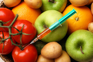 GMO concept. Different vegetables, fruits and syringe in basket, top view
