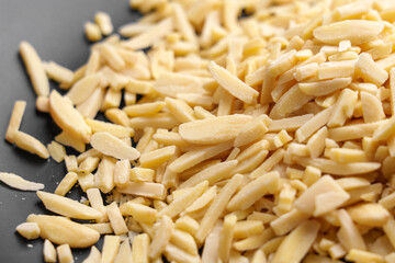 Slivered almonds scattered on a black plate.