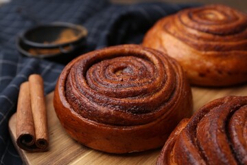 Fototapeta premium Delicious cinnamon rolls on wooden board, closeup