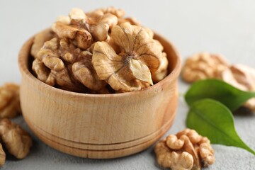 Peeled walnuts in bowl on gray table, closeup