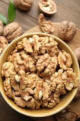 Peeled walnuts in bowl on table, top view