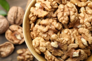 Peeled walnuts in bowl on table, top view
