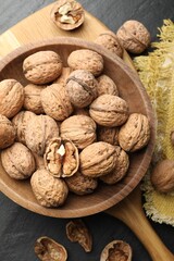Fresh ripe walnuts in shells on black table, flat lay