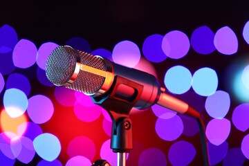Obraz premium Microphone on stand against dark background with blurred lights. Bokeh effect