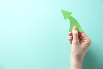 Woman with paper arrow on turquoise background, top view. Space for text