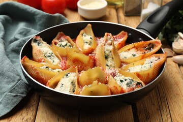 Delicious shell pasta stuffed with ricotta and spinach served on wooden table, closeup