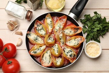 Delicious shell pasta stuffed with ricotta and spinach served on white wooden table, flat lay