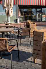 photo Outdoor seating arrangement with wicker chairs and wooden tables in a modern urban setting surrounded by decorative elements and shaded by large umbrellas