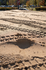 photo Sandy Terrain with Tire Tracks and Footprints Highlighting the Passage of Vehicles and Pedestrians in Natural Outdoor Urban Environment on a Sunny Day