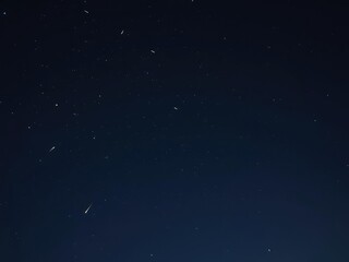 Fototapeta premium Darkened sky with scattered stars and shooting stars streaking across the horizon, celestial motion, fleeting moments