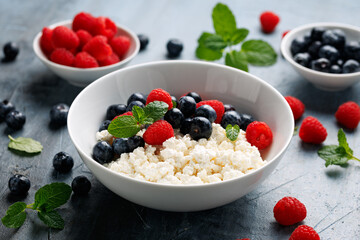 Bowl of cottage cheese, curd cheese with blueberry and raspberry. High protein healthy breakfast or lunch