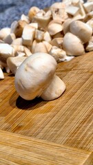 Freshly sliced mushrooms on a wooden cutting board ready for cooking in a kitchen setting