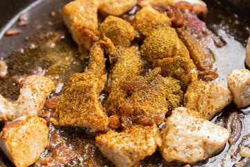 Chicken pieces fried in a frying pan in sauce and spices