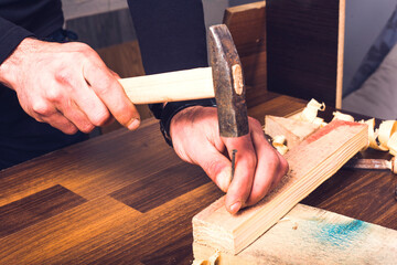 Man hands drive nail with a hammer in wooden
