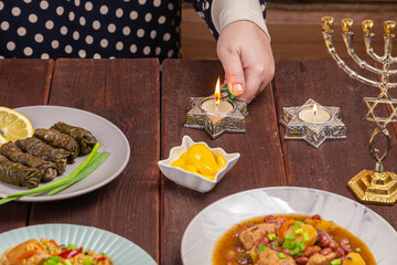 A Jewish woman's hand lights candles on Shabbat in candlesticks