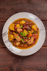 On the plate on the table is chelnt with potatoes, beans, onions, meat, spices