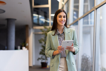 Latina business leader tracking company performance on a tablet in an office