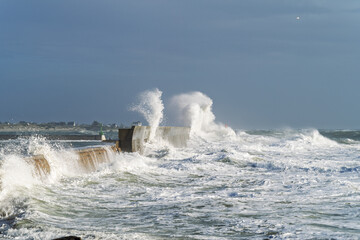 Les vagues déchaînées se fracassent contre la jetée de Lesconil, projetant des gerbes d'écume immaculée sous un ciel d’azur. La mer en furie livre un spectacle saisissant.