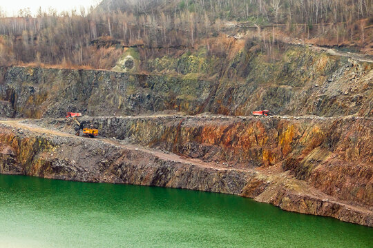 Open pit mining of minerals in Ukraine. Granite quarry with a lake. Mining machinery on the slopes of the quarry. Surface mining