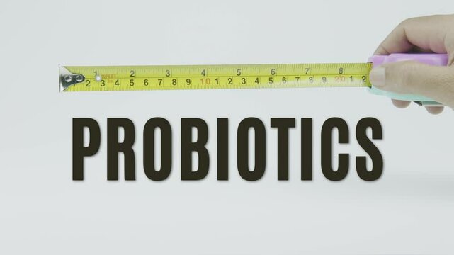 "Probiotics" text with a yellow tape measure on a white background, symbolizing precision, accuracy, and the measurement of gut health and beneficial bacteria in a clean, minimal video