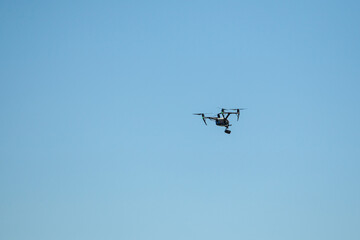 Drone flying with a camera against blue sky