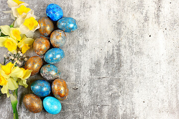 Happy Easter concept. Abstract Easter composition with marbled blue-gray decorated eggs and blooming daffodils, painted with hibiscus flowers. Banner for the screen with space for greeting text