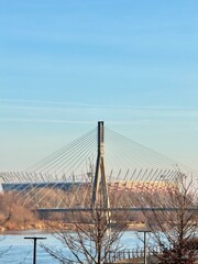 view of a warsaw bridge over the vistula with a view of the olympic stadium in the background on a sunny winter day
